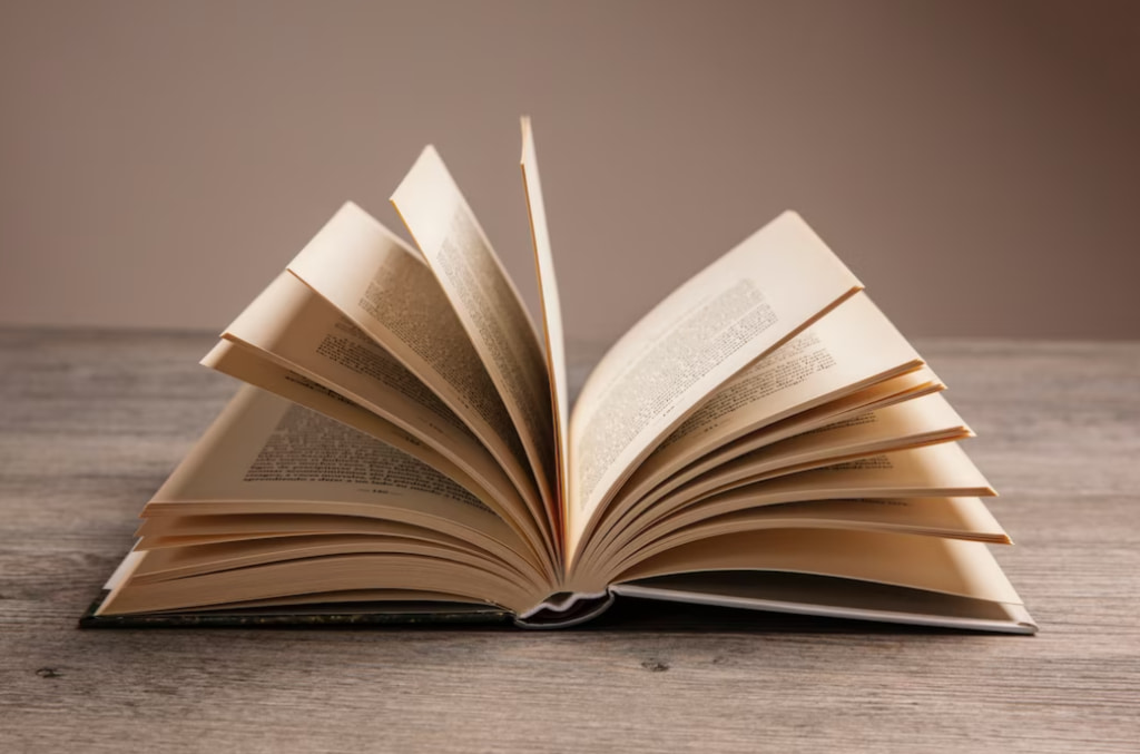 An open book lies on a wooden surface, pages fluttering